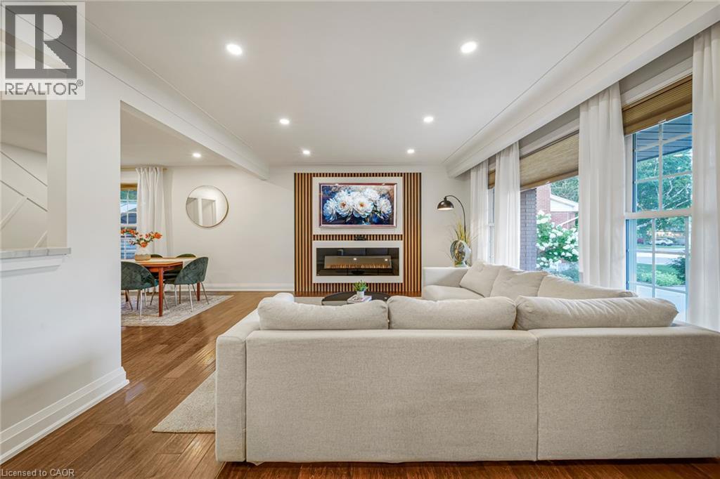 Hardwood flooring, recessed ceiling lighting, a built-in fireplace, and expansive windows - 24 Garvey Crescent, Hamilton, ON - Indoor Photo Showing Living Room With Fireplace