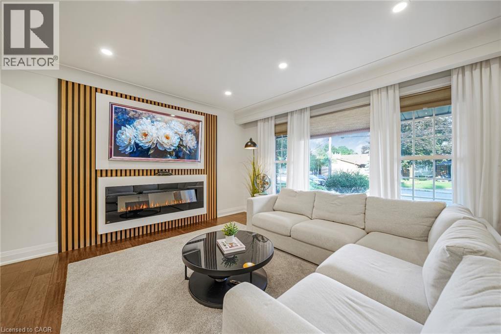 Wood-finish flooring, recessed lighting, and a linear electric fireplace with a wood slat accent wall - 24 Garvey Crescent, Hamilton, ON - Indoor Photo Showing Living Room With Fireplace