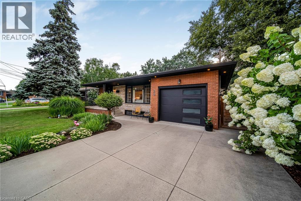 Brick and stone exterior with a black garage door and modern windows - 24 Garvey Crescent, Hamilton, ON - Outdoor