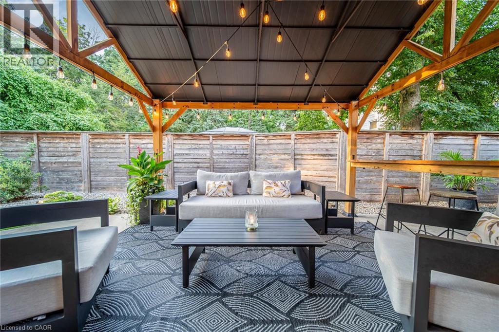 Outdoor covered patio featuring exposed wood beams, a dark metal roof, and string lighting - 24 Garvey Crescent, Hamilton, ON - Outdoor With Deck Patio Veranda With Exterior