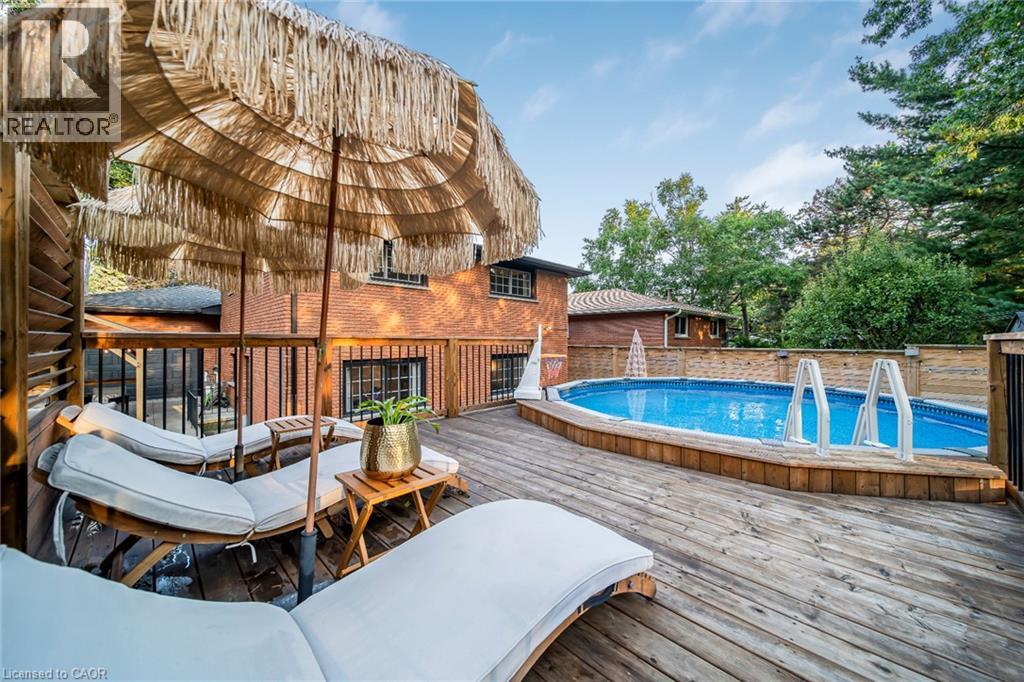 Expansive wood-finish deck with a built-in above-ground pool, surrounded by privacy fencing and mature trees - 24 Garvey Crescent, Hamilton, ON - Outdoor With Above Ground Pool With Deck Patio Veranda