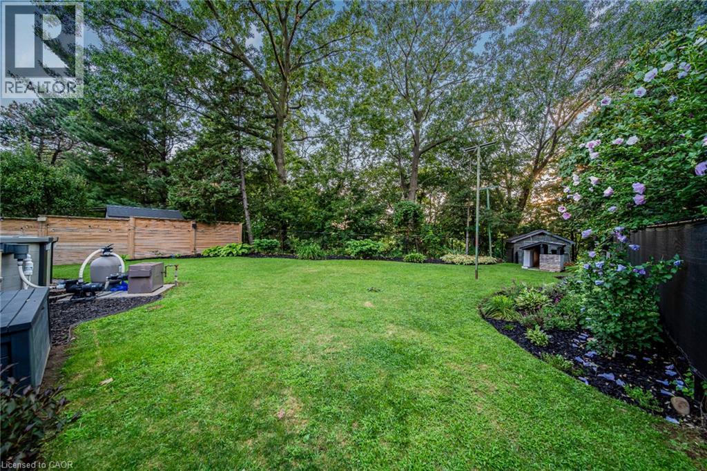 Expansive lawn with mature trees, established perimeter landscaping, wood fencing, and a garden shed - 24 Garvey Crescent, Hamilton, ON - Outdoor