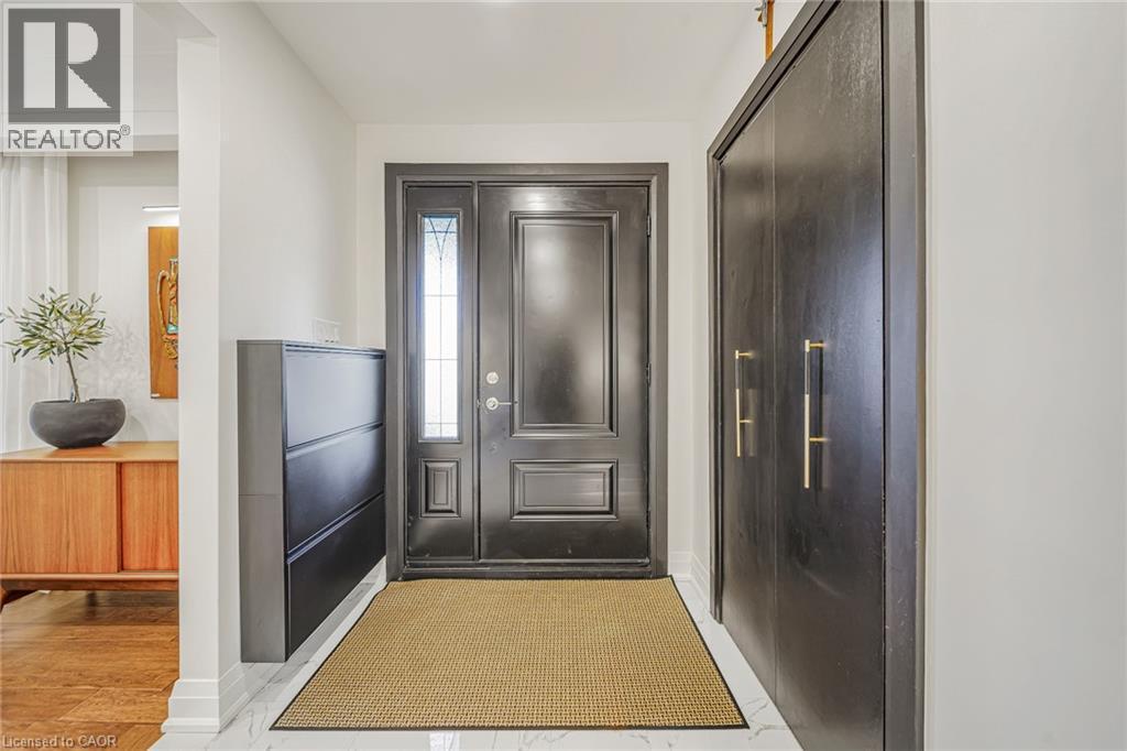 Entryway featuring a dark paneled door with decorative glass inserts, white baseboards, and a dark wood-finish built-in storage unit with gold-tone hardware - 24 Garvey Crescent, Hamilton, ON - Indoor Photo Showing Other Room