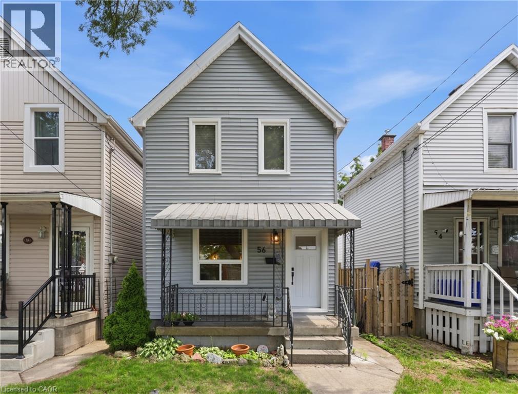 Two-story exterior with horizontal siding, a covered front porch with metal railings, and a white entry door - 56 Harmony Avenue, Hamilton, ON - Outdoor With Deck Patio Veranda