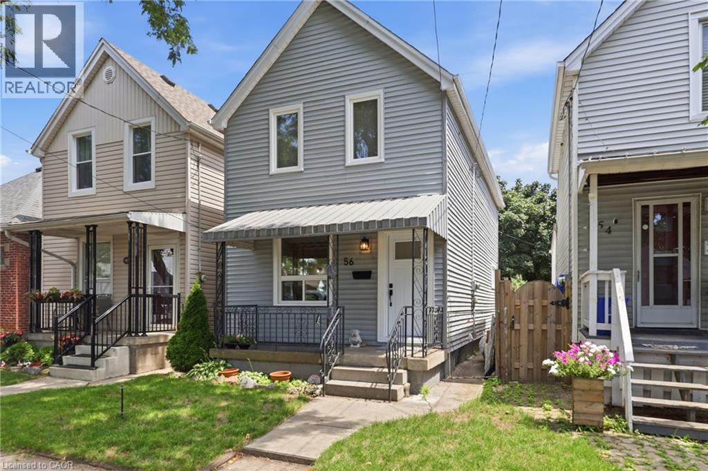 Light gray horizontal siding exterior with a pitched roof, front porch with an awning, black wrought iron railing, and concrete steps - 56 Harmony Avenue, Hamilton, ON - Outdoor With Deck Patio Veranda With Facade