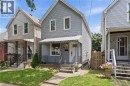 Light gray horizontal siding exterior with a pitched roof, front porch with an awning, black wrought iron railing, and concrete steps - 56 Harmony Avenue, Hamilton, ON  - Outdoor With Deck Patio Veranda With Facade 