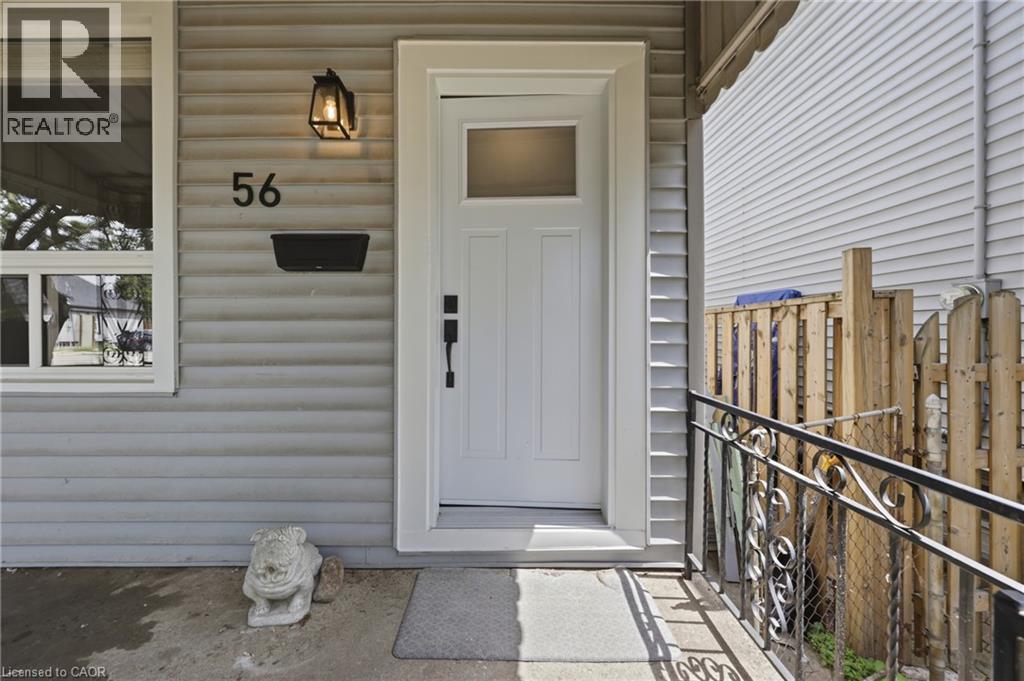 White entry door with a frosted glass pane and black hardware, complemented by a black exterior light fixture - 56 Harmony Avenue, Hamilton, ON - Outdoor With Exterior