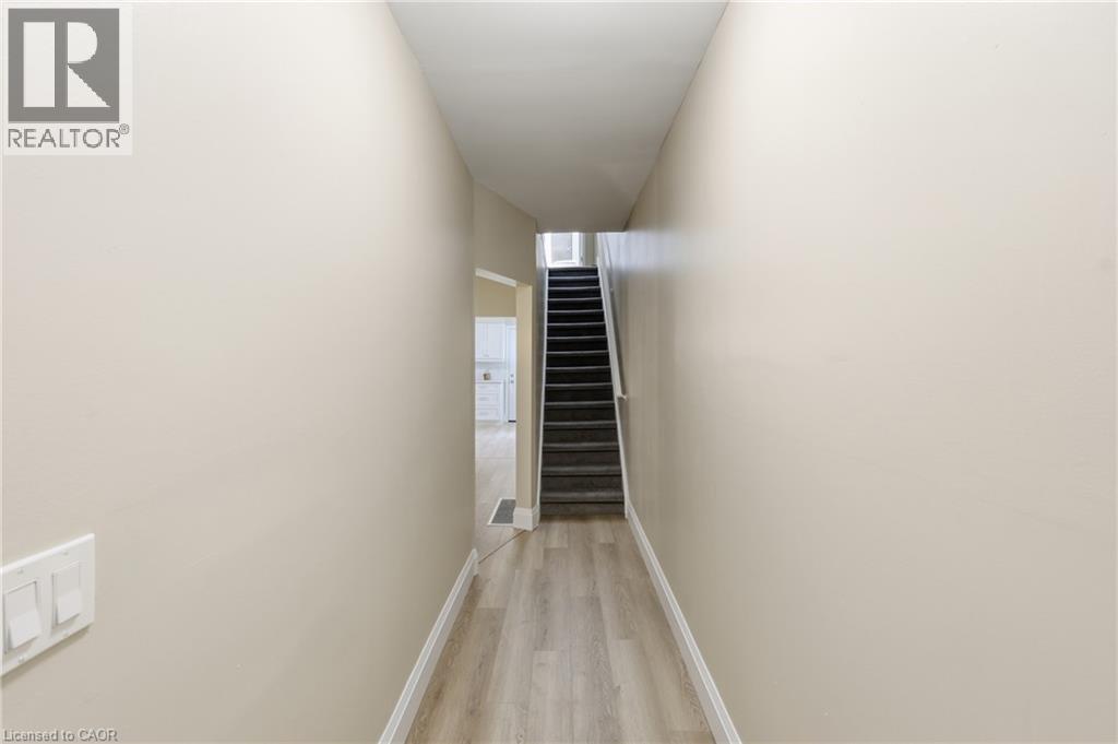 Hallway featuring wood-finish flooring, light-toned walls, and a carpeted staircase - 56 Harmony Avenue, Hamilton, ON - Indoor Photo Showing Other Room