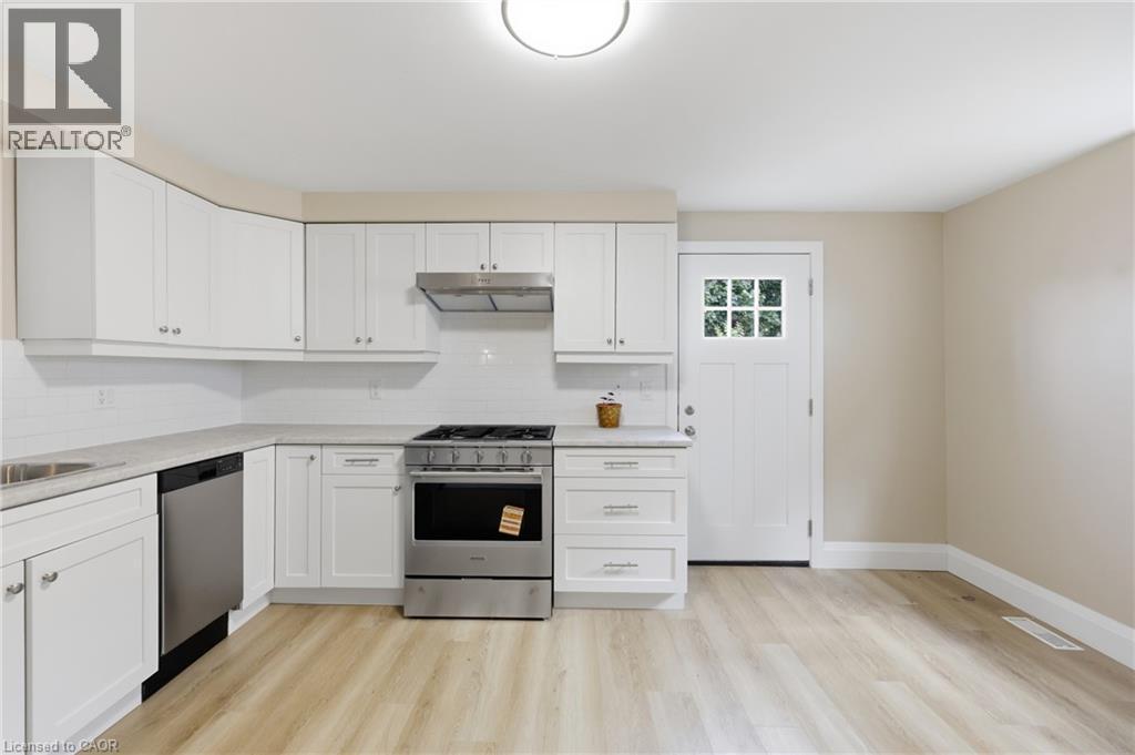 Bright kitchen featuring white cabinetry, light countertops, wood-finish flooring, a stainless steel gas range, and a dishwasher - 56 Harmony Avenue, Hamilton, ON - Indoor Photo Showing Kitchen