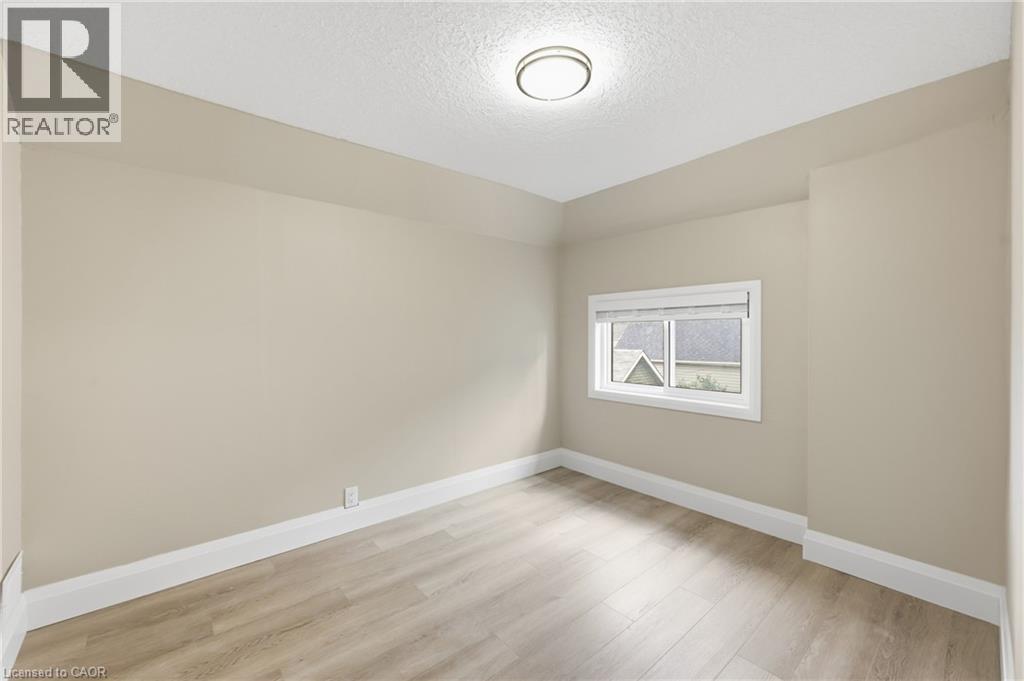 Recessed window with blinds, wood-finish flooring, and a flush-mount ceiling light - 56 Harmony Avenue, Hamilton, ON - Indoor Photo Showing Other Room