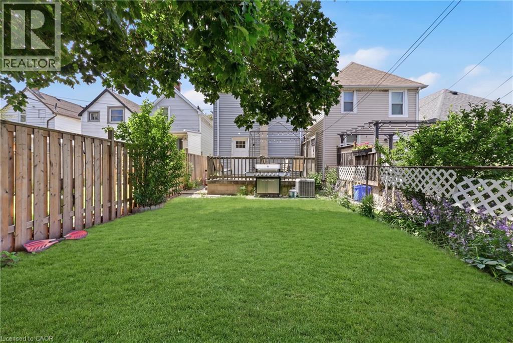 Expansive green lawn with a wood privacy fence, wood deck, and a white lattice fence - 56 Harmony Avenue, Hamilton, ON - Outdoor