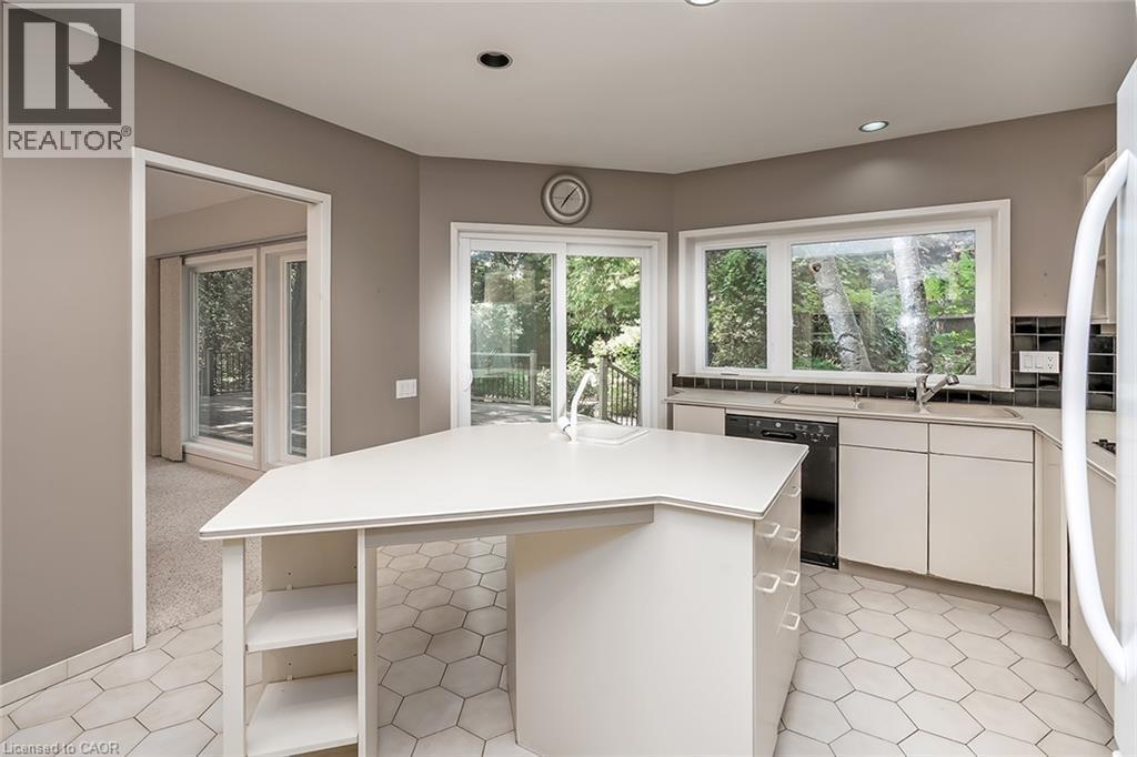 Kitchen featuring a center island, white cabinetry, integrated sink, and an appliance suite - 4189 Inglewood Drive, Burlington, ON - Indoor Photo Showing Kitchen With Double Sink