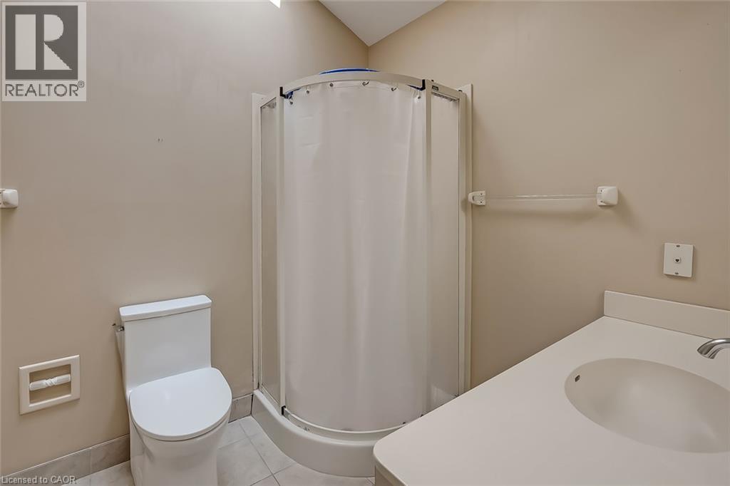 Compact three-fixture bathroom featuring a white toilet, corner shower enclosure, and a vanity with an integrated sink - 4189 Inglewood Drive, Burlington, ON - Indoor Photo Showing Bathroom