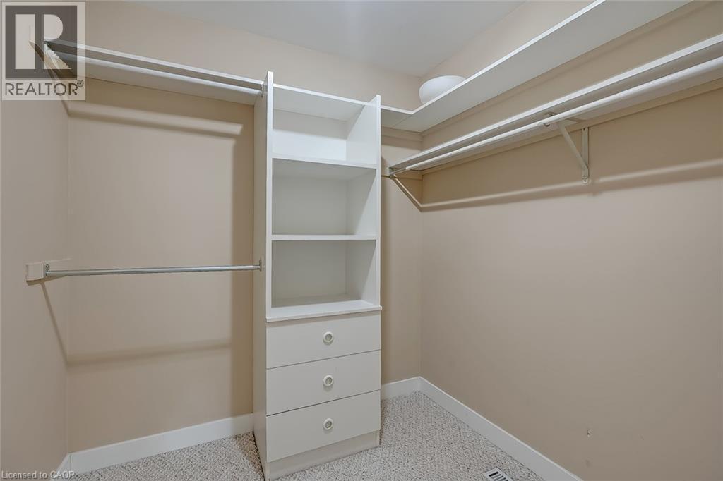 Carpeted walk-in closet featuring built-in shelving, multiple hanging rods, and integrated drawers - 4189 Inglewood Drive, Burlington, ON - Indoor With Storage
