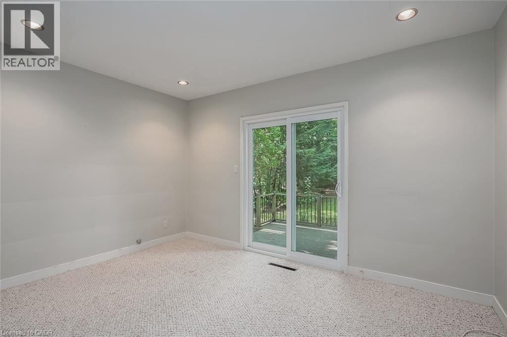Recessed ceiling lighting, light gray wall paint, patterned carpeting, and white sliding glass doors opening to an exterior deck - 4189 Inglewood Drive, Burlington, ON - Indoor Photo Showing Other Room