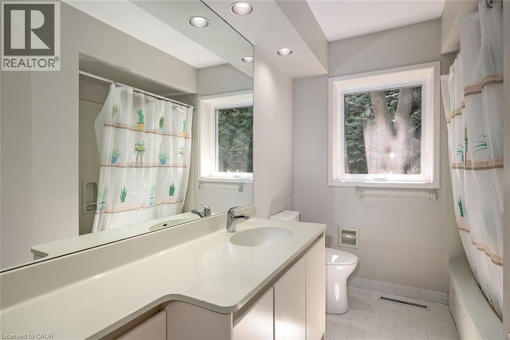 White vanity with integrated sink, chrome faucet, and expansive mirror - 4189 Inglewood Drive, Burlington, ON - Indoor Photo Showing Bathroom