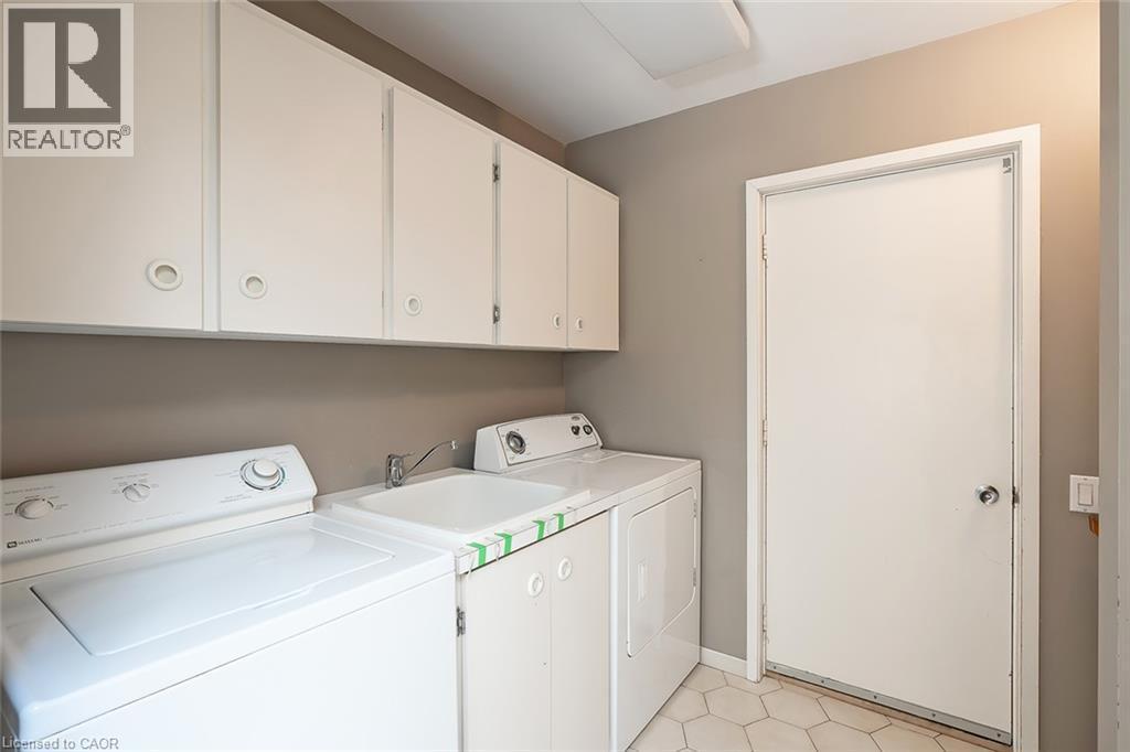 Upper cabinetry with recessed pulls, utility sink, and hexagonal floor tile - 4189 Inglewood Drive, Burlington, ON - Indoor Photo Showing Laundry Room