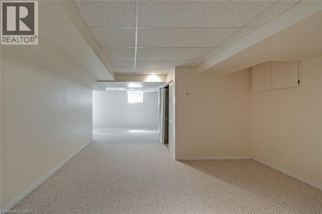 Expansive open room featuring neutral wall paint, textured carpet, and a drop ceiling - 4189 Inglewood Drive, Burlington, ON - Indoor