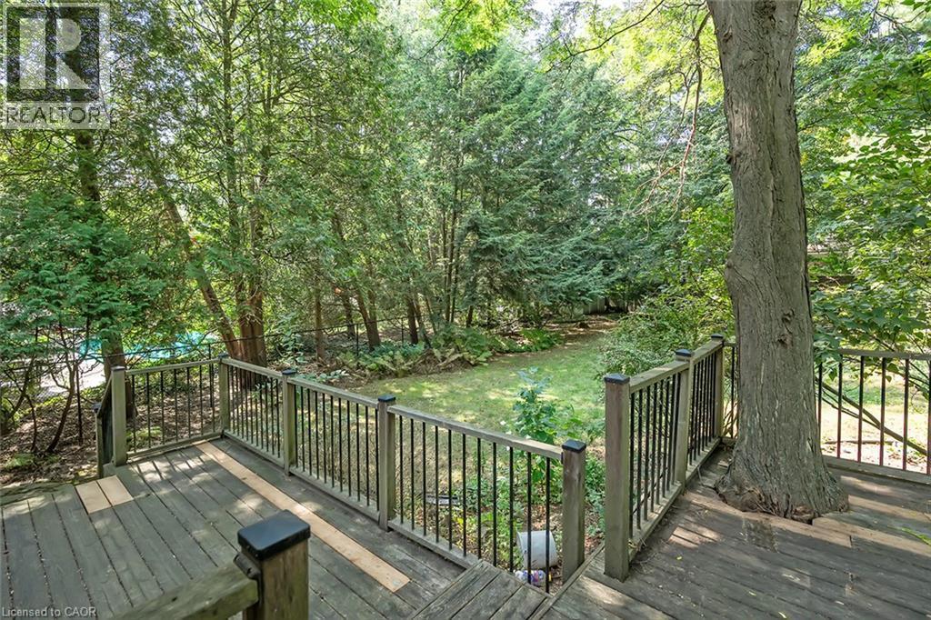 Expansive outdoor decking with metal balusters, mature trees, and a grassy area - 4189 Inglewood Drive, Burlington, ON - Outdoor