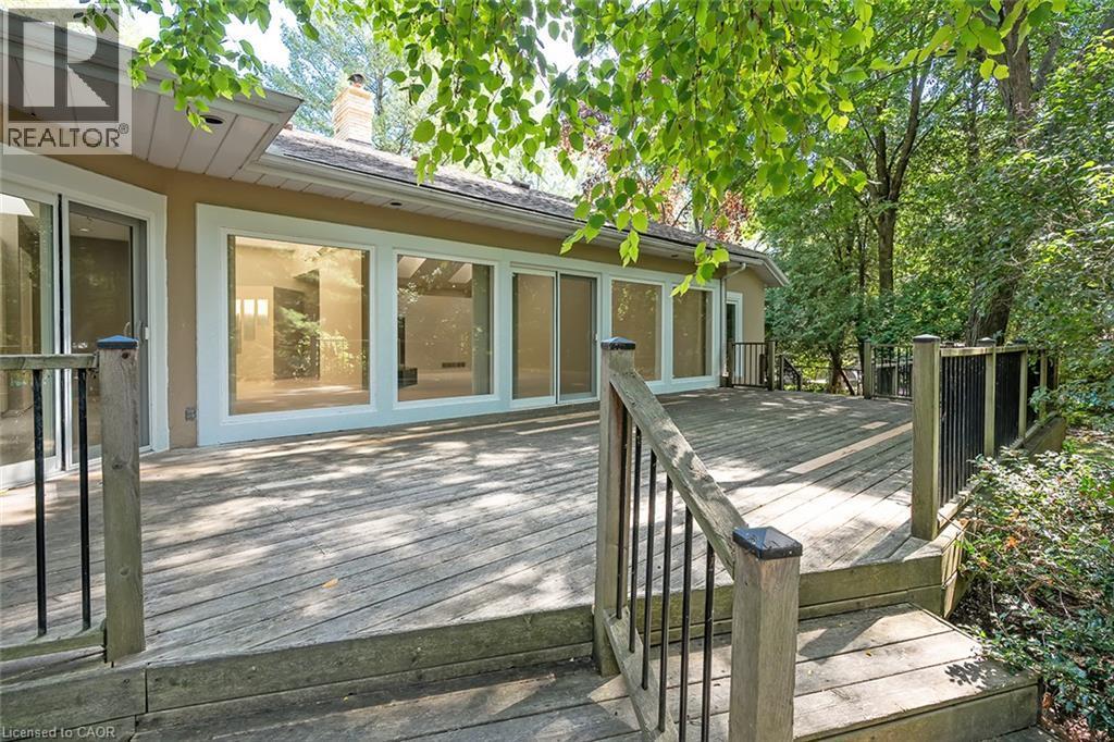 Expansive wood deck with a perimeter railing, multiple glass sliding doors, and large windows - 4189 Inglewood Drive, Burlington, ON - Outdoor With Deck Patio Veranda