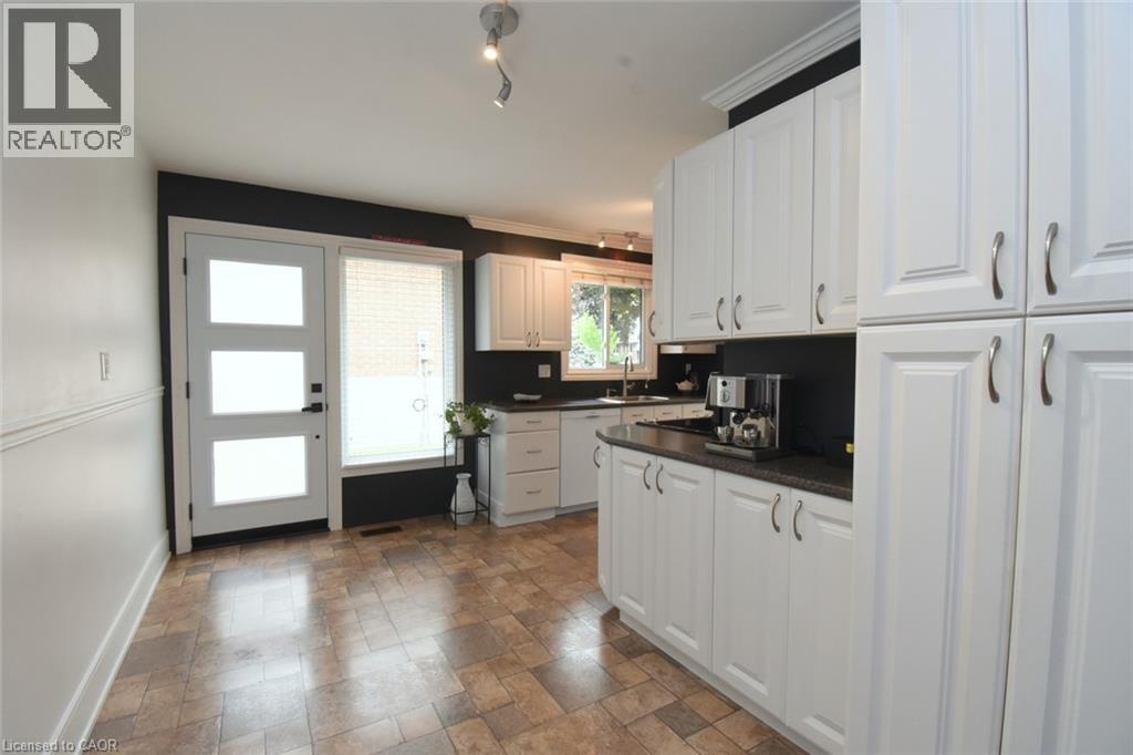 Kitchen featuring extensive white cabinetry, dark countertops, and a stainless steel sink - 374 Brigadoon Drive, Hamilton, ON - Indoor Photo Showing Kitchen