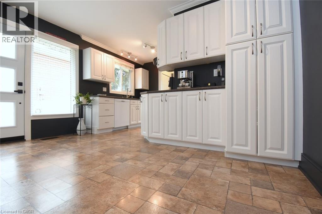 White shaker-style cabinetry, dark countertops, tiled flooring, and a glass-paneled door - 374 Brigadoon Drive, Hamilton, ON - Indoor Photo Showing Kitchen