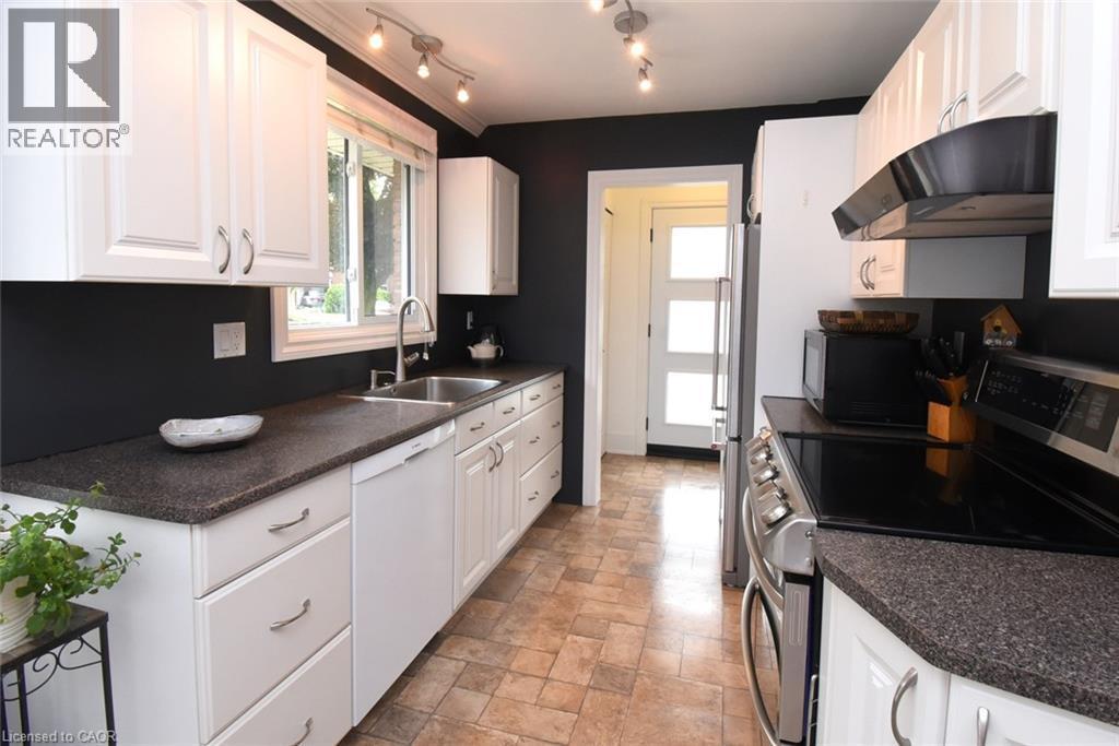White shaker-style cabinetry, dark speckled countertops, stainless steel sink with gooseneck faucet, integrated dishwasher, and track lighting - 374 Brigadoon Drive, Hamilton, ON - Indoor Photo Showing Kitchen