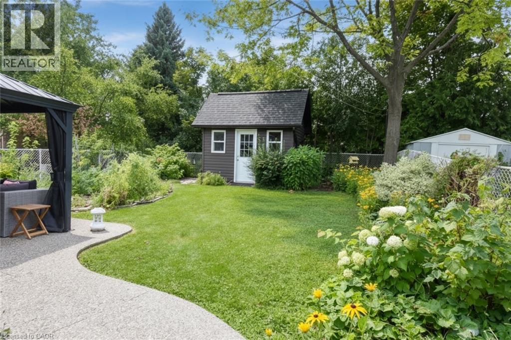 Manicured lawn with a curved concrete pathway leading to a shaded gazebo and a detached storage shed - 374 Brigadoon Drive, Hamilton, ON - Outdoor
