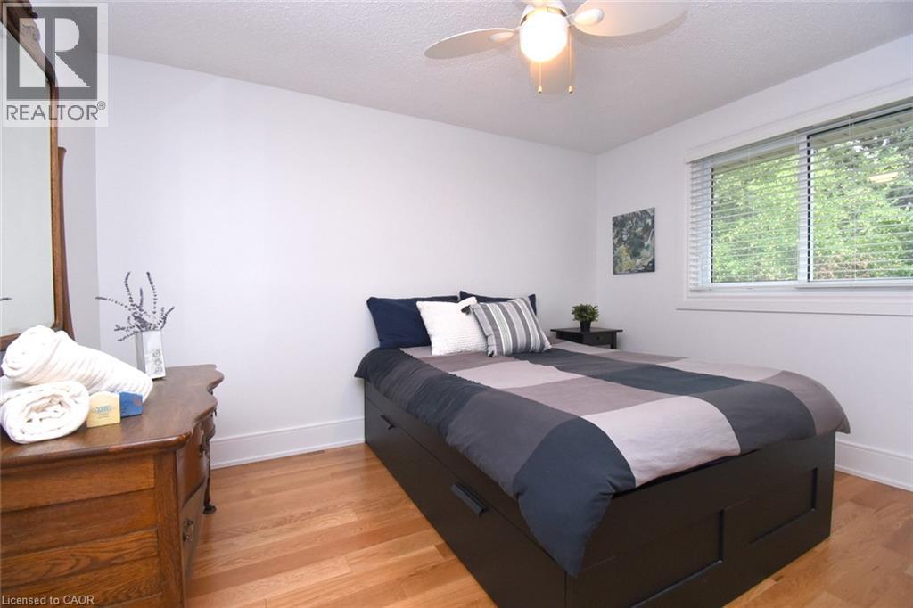 Hardwood flooring, overhead ceiling fan with light fixture, large window with blinds, white trim, and white walls - 374 Brigadoon Drive, Hamilton, ON - Indoor Photo Showing Bedroom