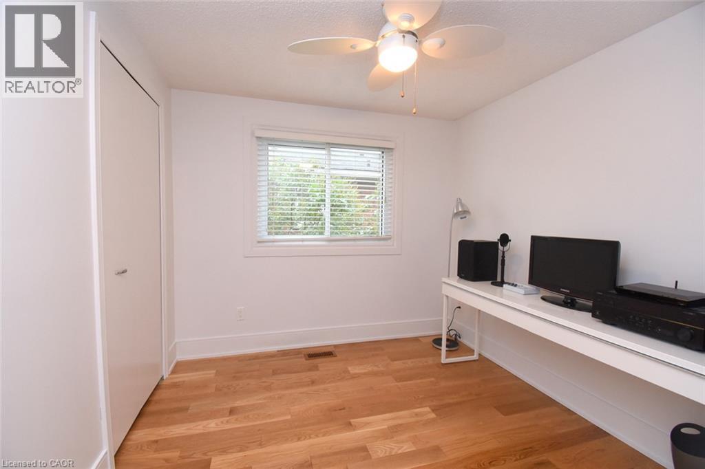 Hardwood flooring, window with blinds, ceiling fan with integrated lighting, built-in desk, and a closet with a bifold door - 374 Brigadoon Drive, Hamilton, ON - Indoor Photo Showing Office