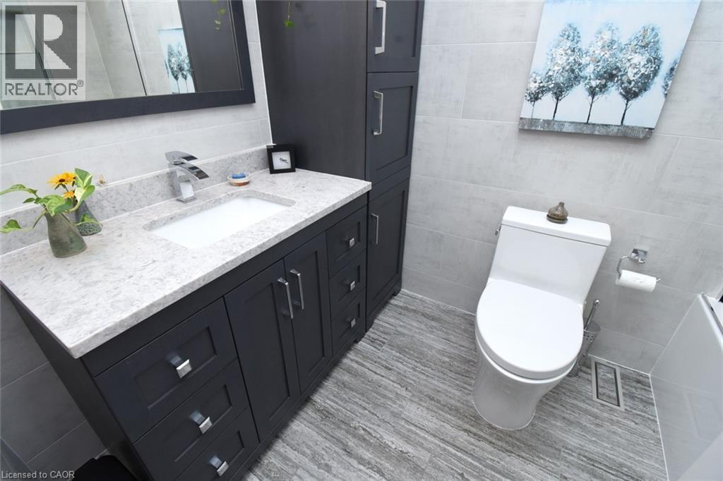 Modern vanity with a light-toned countertop, under-mount sink, and chrome faucet - 374 Brigadoon Drive, Hamilton, ON - Indoor Photo Showing Bathroom
