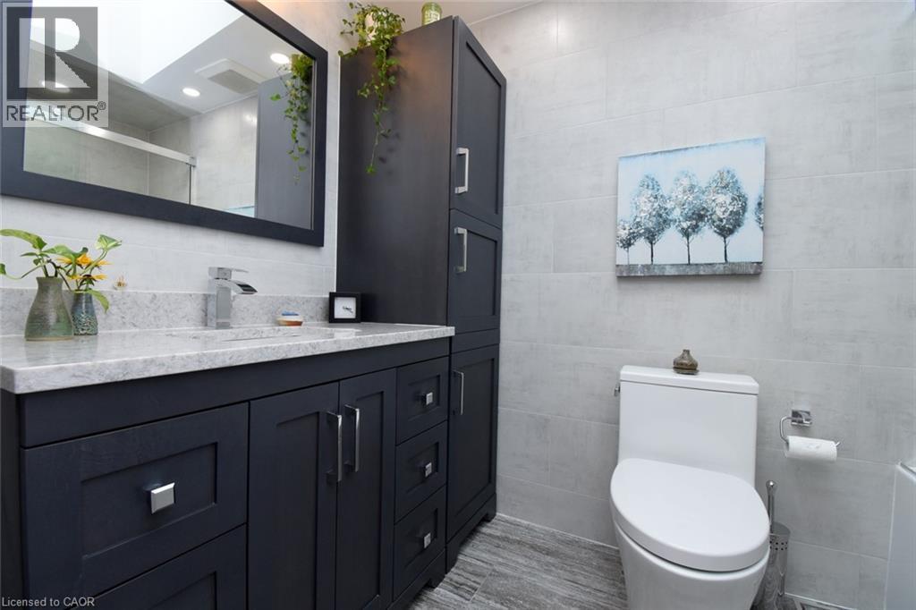 Dark wood-finish vanity with a light-toned countertop, rectangular sink, and chrome faucet - 374 Brigadoon Drive, Hamilton, ON - Indoor Photo Showing Bathroom