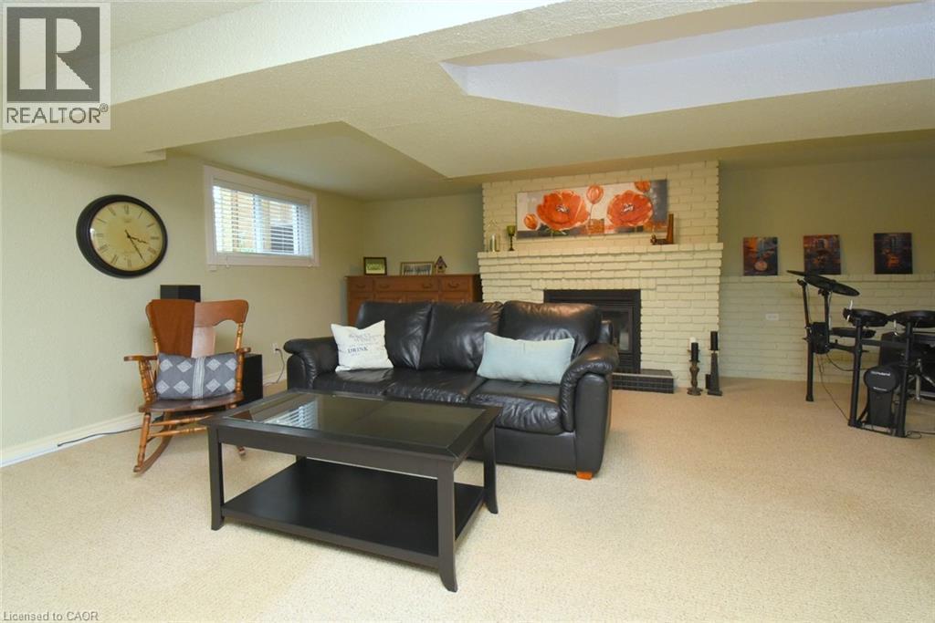 Recessed window with blinds, light-colored carpeting, and a brick-faced fireplace with a dark-toned hearth - 374 Brigadoon Drive, Hamilton, ON - Indoor Photo Showing Living Room