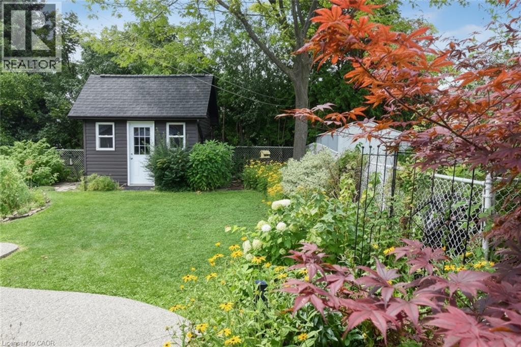 Manicured lawn with a detached storage shed, lush garden beds, and mature trees - 374 Brigadoon Drive, Hamilton, ON - Outdoor