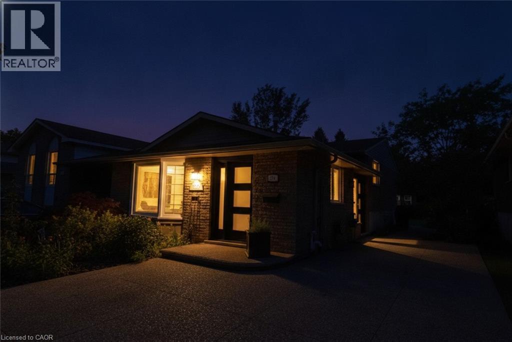 Brick facade with a contemporary entry door, exterior lighting, and a paved driveway - 374 Brigadoon Drive, Hamilton, ON - Outdoor
