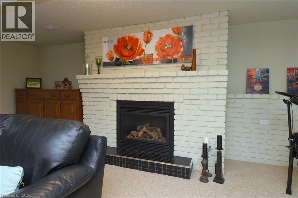 Whitewashed brick fireplace featuring a black tile hearth and a built-in firebox - 374 Brigadoon Drive, Hamilton, ON - Indoor With Fireplace