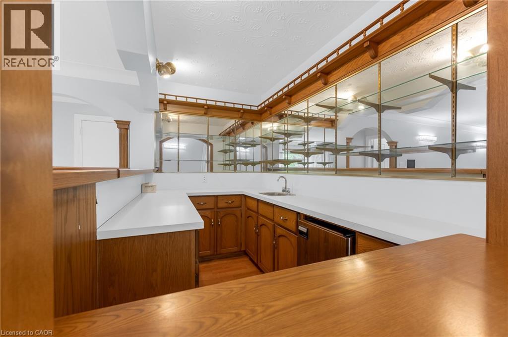 Custom wet bar featuring wood-finish cabinetry, solid surface countertops, and an undermount sink - 35 Glen Park Court, Hamilton, ON - Indoor Photo Showing Kitchen