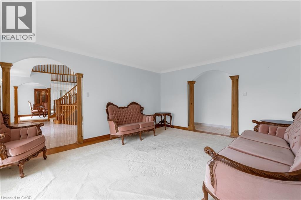 Expansive room featuring light-colored walls, crown molding, and an arched entryway with decorative wood columns - 35 Glen Park Court, Hamilton, ON - Indoor Photo Showing Living Room