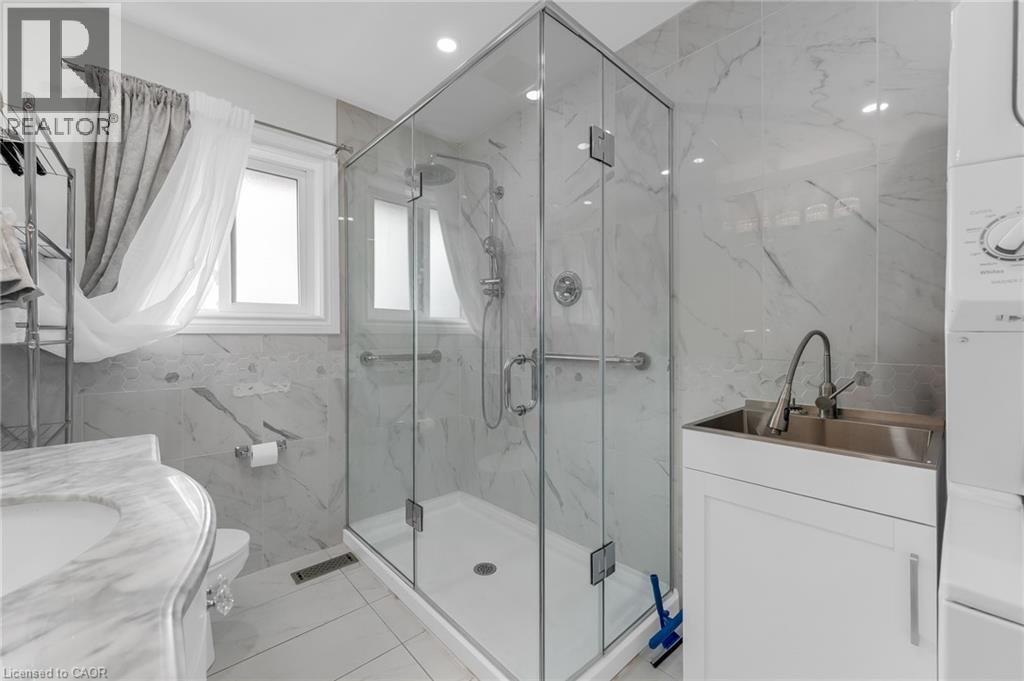 Glass-enclosed shower with a rainfall showerhead, white marble-look wall tiling, and a window for natural light - 35 Glen Park Court, Hamilton, ON - Indoor Photo Showing Bathroom
