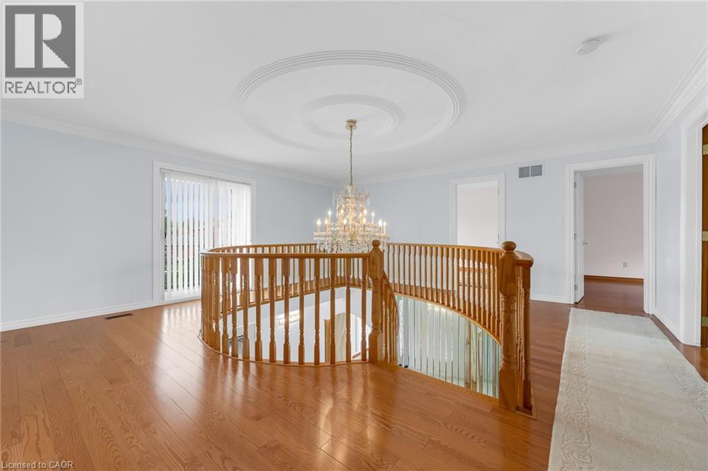 Hardwood flooring, curved wood balustrade, ceiling medallion, chandelier, and a sliding glass door - 35 Glen Park Court, Hamilton, ON - Indoor Photo Showing Other Room