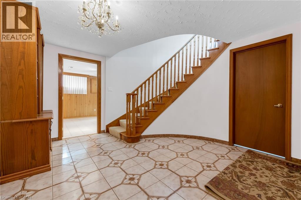 Entryway featuring patterned tile flooring, a curved staircase with wood banister, and a chandelier - 35 Glen Park Court, Hamilton, ON - Indoor Photo Showing Other Room