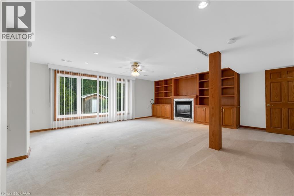 Spacious room with recessed lighting, integrated wood cabinetry, a fireplace with a stone surround, and large windows - 35 Glen Park Court, Hamilton, ON - Indoor With Fireplace