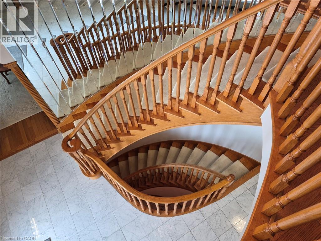 Curved staircase featuring wood balusters, a wood handrail, and carpeted treads - 35 Glen Park Court, Hamilton, ON - Indoor Photo Showing Other Room