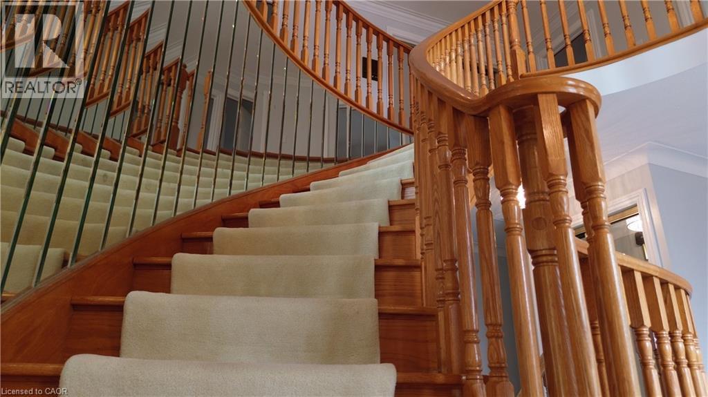 Curved staircase featuring wood balusters, wood handrail, and carpeted treads - 35 Glen Park Court, Hamilton, ON - Indoor Photo Showing Other Room