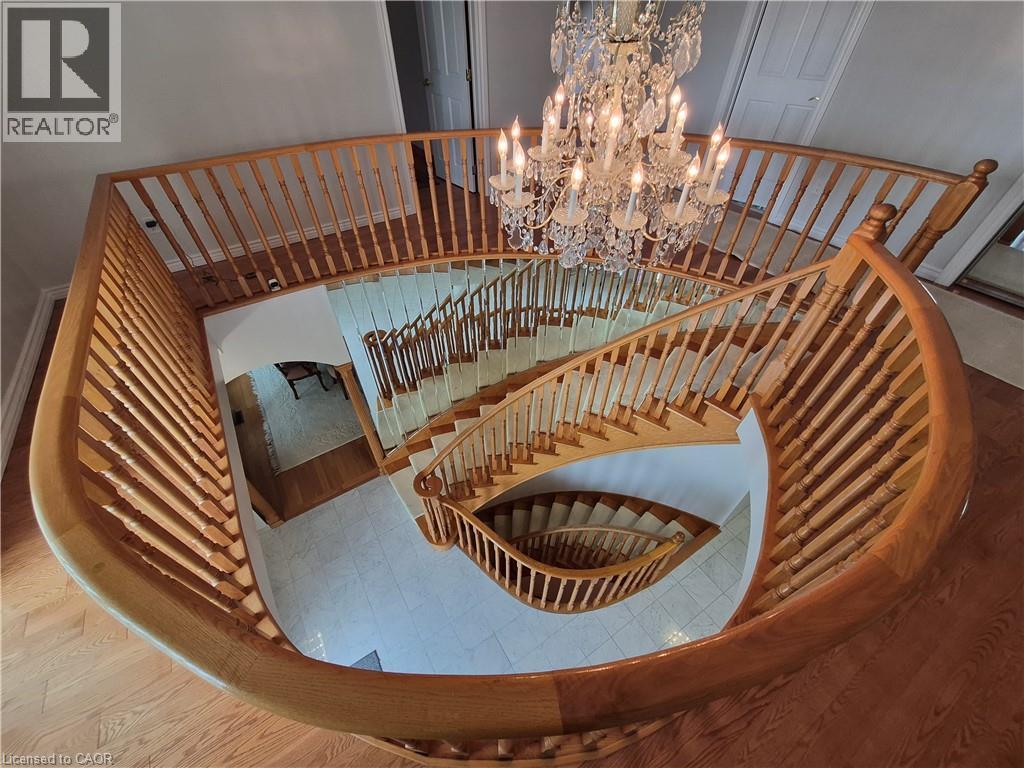 Spiral staircase with wood banister, crystal chandelier, wood-finish flooring, and light-toned tile - 35 Glen Park Court, Hamilton, ON - Indoor Photo Showing Other Room
