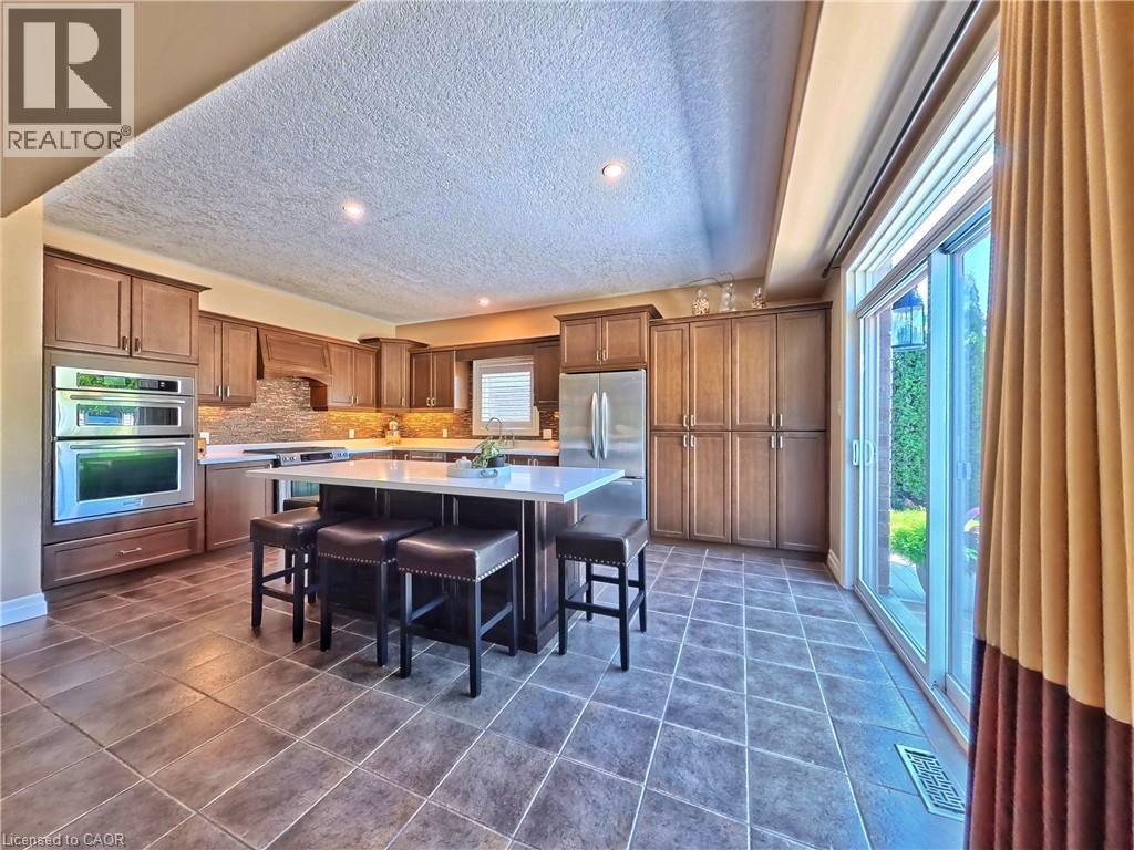 Gourmet kitchen featuring custom wood cabinetry, stainless steel appliances, quartz countertops, and a large center island with seating - 913 Valebrook Court, Kitchener, ON - Indoor
