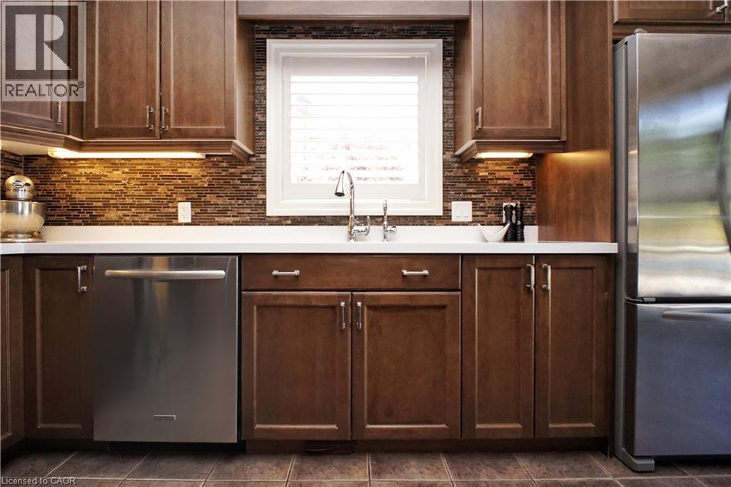 Full-height cabinetry with under-cabinet lighting, mosaic tile backsplash, stainless steel appliances, and a window with blinds - 913 Valebrook Court, Kitchener, ON - Indoor Photo Showing Kitchen