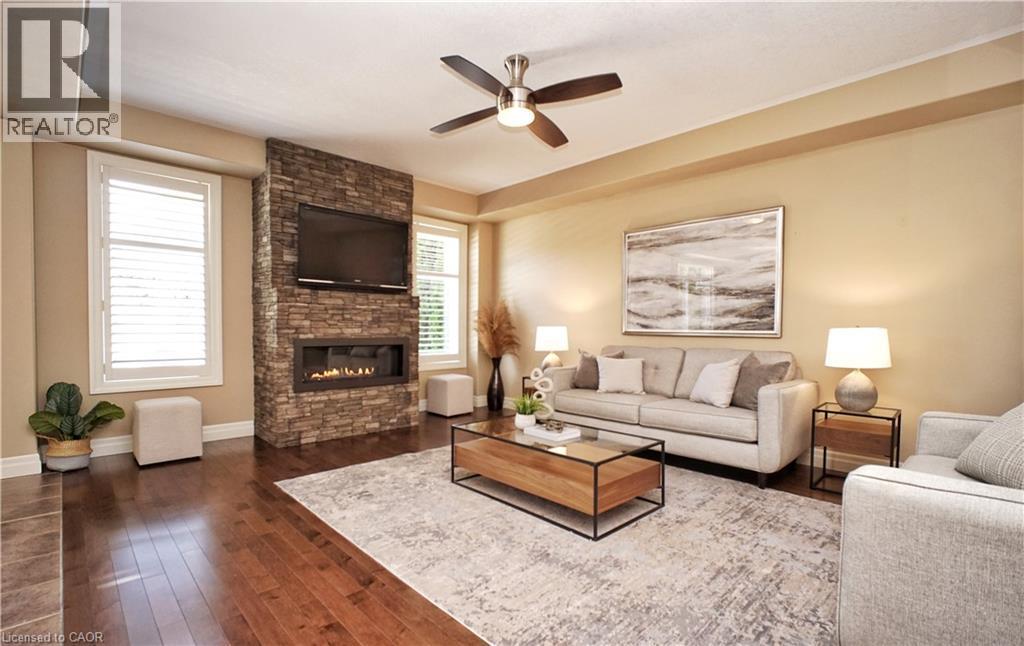 Hardwood flooring throughout, stone-clad fireplace with built-in linear electric insert, and ceiling fan with integrated lighting - 913 Valebrook Court, Kitchener, ON - Indoor Photo Showing Living Room With Fireplace