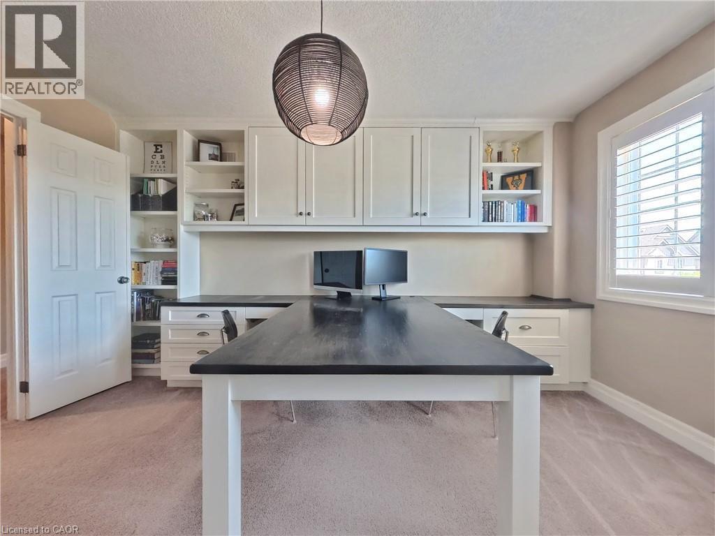 Sophisticated home office featuring a spacious black-topped work island with white base cabinetry, wall-mounted shelving with open storage, recessed lighting, pendant fixture overhead, and abundant na - 913 Valebrook Court, Kitchener, ON - Indoor