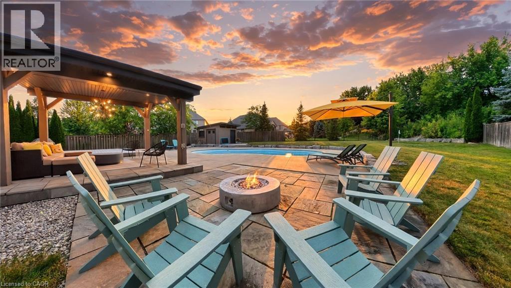 Expansive backyard featuring a built-in swimming pool, stone paver patio, wood gazebo with integrated lighting, a fire pit, and mature landscaping - 913 Valebrook Court, Kitchener, ON - Outdoor With In Ground Pool With Deck Patio Veranda